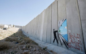 ABU DIS, WEST BANK - AUGUST 6. A graffiti made by the graffiti artist Banksy is seen on Israel's highly controversial West Bank barrier in Abu Dis on August 6, 2005. Banksy has made a name for himself with provocative images stencilled around the streets of London.On his recent trip to the Palestinian territories he has created nine of his images on Israel's highly controversial West Bank barrier. (Photo by Marco Di Lauro/Getty Images)